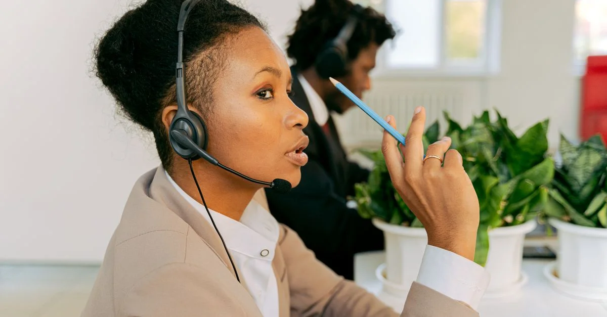 Zwei Callcenter-Agenten, die sich auf den Kundenservice konzentrieren, mit Headsets in einem Büro.