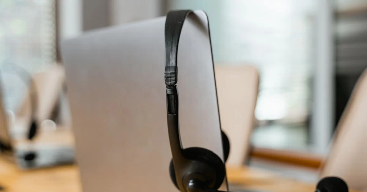 Ein Headset, das an einem Computer in einer modernen Büroumgebung für den Kundenservice hängt.