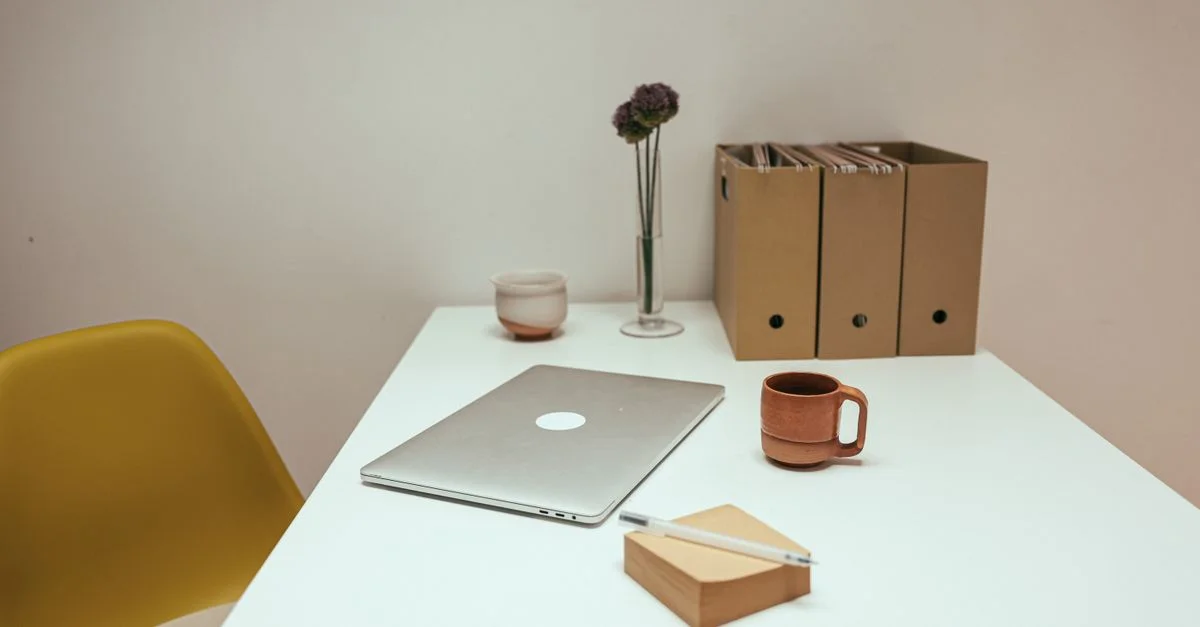 Ein minimalistischer Arbeitsplatz mit einem Laptop, Kaffeetasse, Akten und einer einfachen Dekoration in einem Innenbüro.
