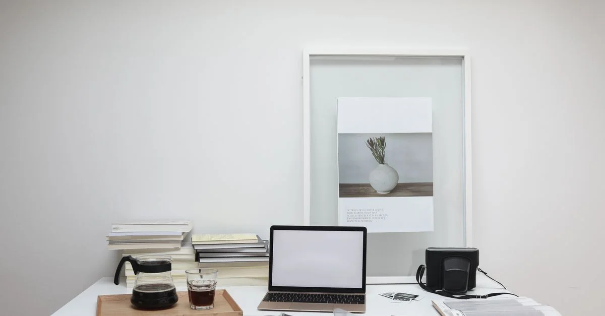Ein stilvoller Arbeitsplatz mit Laptop, Kaffee und Kunst in einer modernen Büroumgebung.