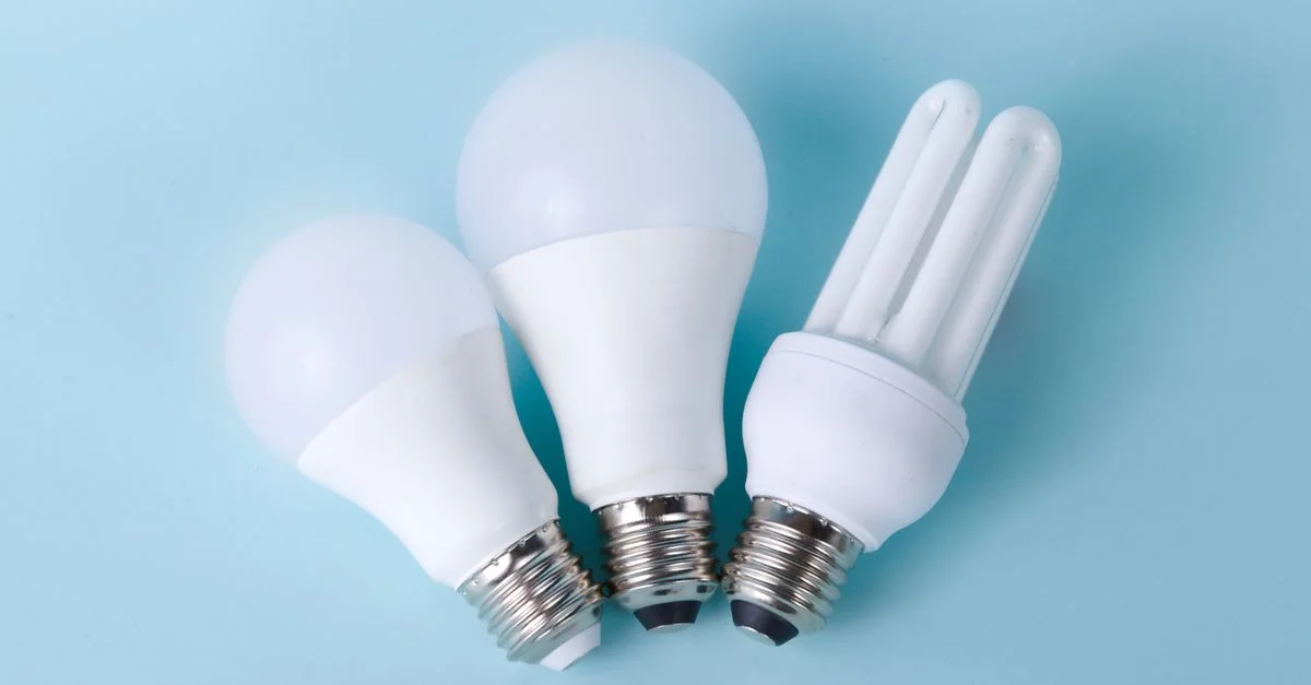 Drei verschiedene LED- und CFL-Glühbirnen vor einem hellblauen Hintergrund.