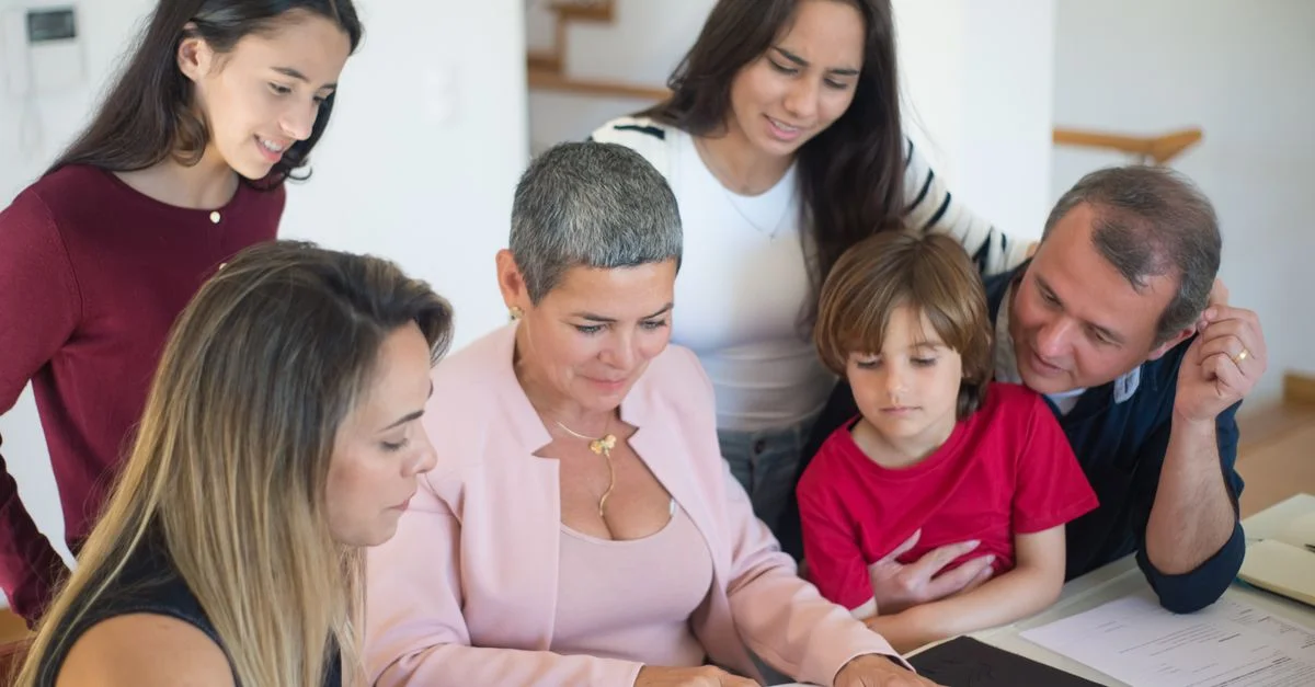 Eine Familie diskutiert zu Hause Immobilienunterlagen mit einem Makler, was die Kommunikation und Planung fördert.
