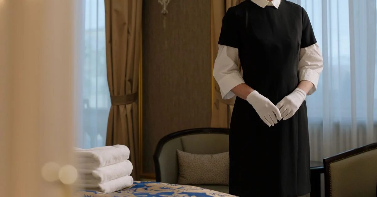 Eine Reinigungskraft in Uniform bereitet ein Luxus-Hotelzimmer vor und zeigt Professionalität und Service.
