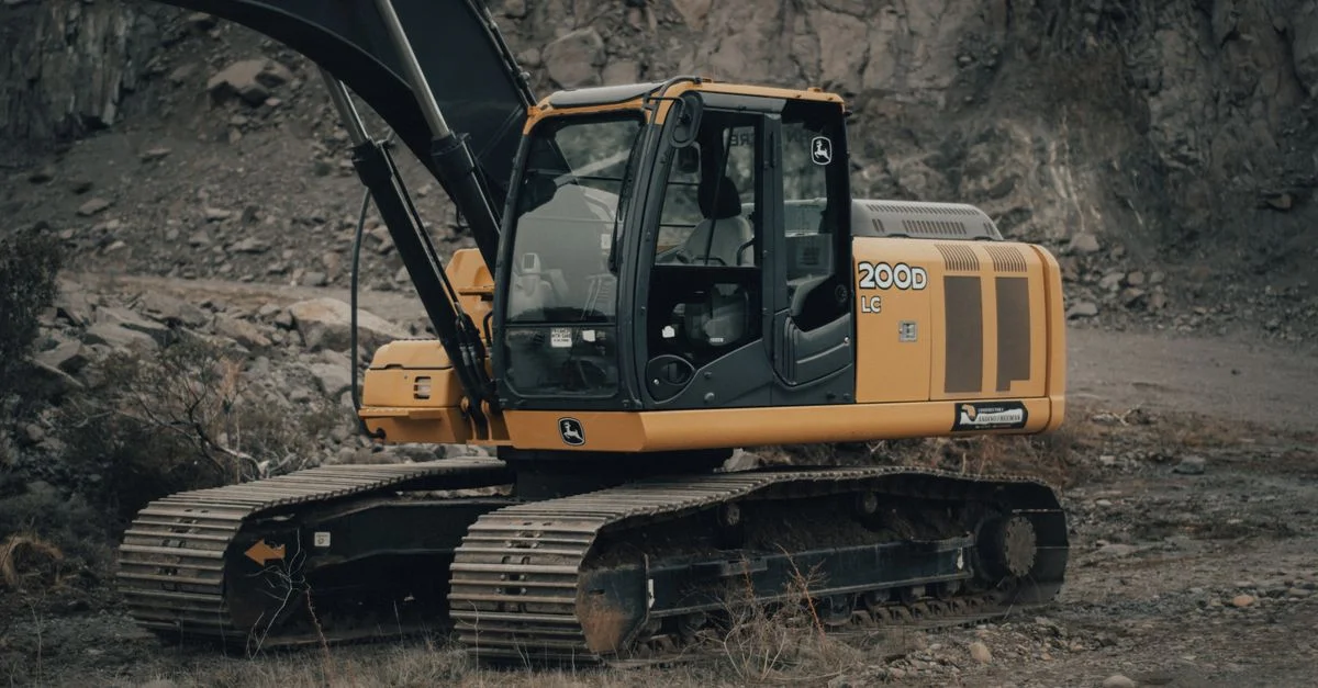 Ein gelber Bagger, der an einem bewölkten Tag in einem steinigen Steinbruch arbeitet.