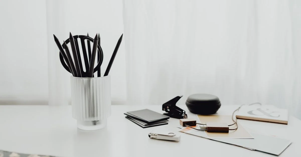 Ein sauberer weißer Schreibtisch mit Büromaterial und Schreibwaren im minimalistischen Stil.