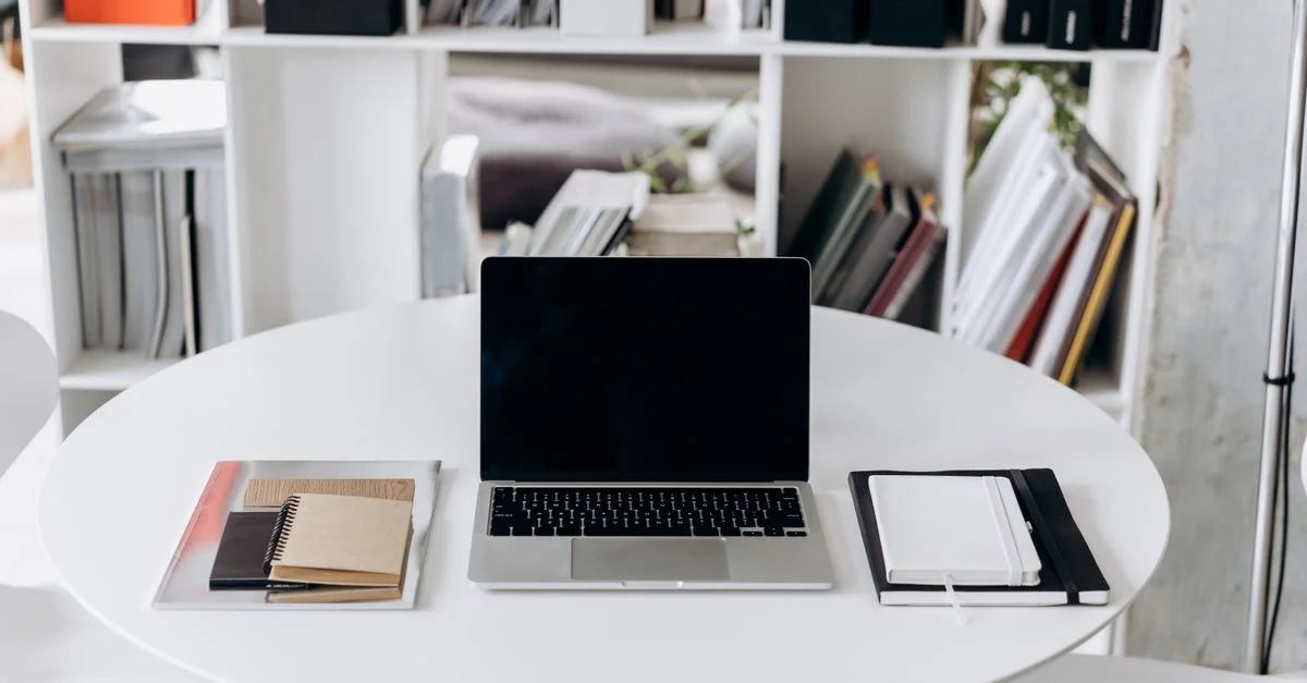 Ein elegantes Büro-Setup mit einem Laptop, Notizbüchern und stilvollen Möbeln, ideal für Produktivität.